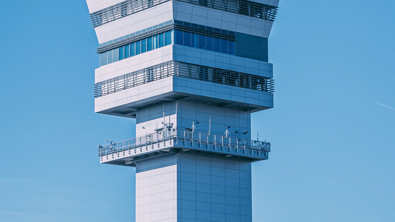 A panel-clad control tower against a clear blue sky